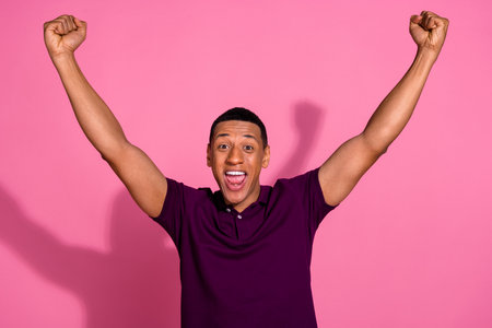 Photo portrait of nice young male raise fists celebrate winner dressed stylish violet garment isolated on pink color backgroundの写真素材