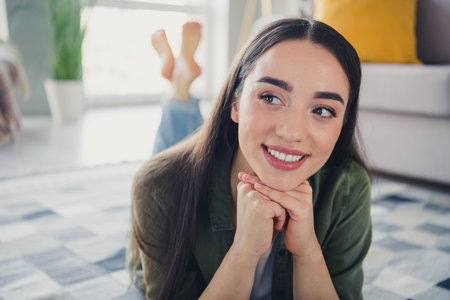 Portrait of nice young girl laying floor fantasize wear green shirt modern interior flat indoorsの写真素材