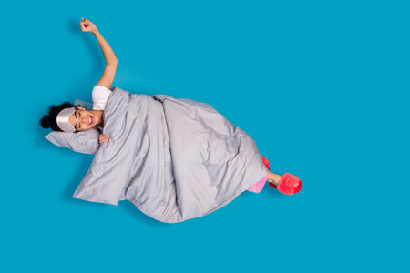 Full size photo of nice young woman stretch bed wear pajama isolated on blue color background