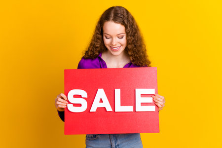 Photo portrait of lovely young lady look hold sale plate dressed stylish violet garment isolated on yellow color backgroundの写真素材