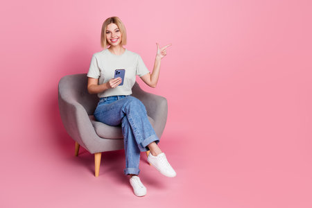 Photo of pretty adorable girl wear stylish grey clothes sit comfy chair empty space isolated on pink color backgroundの写真素材
