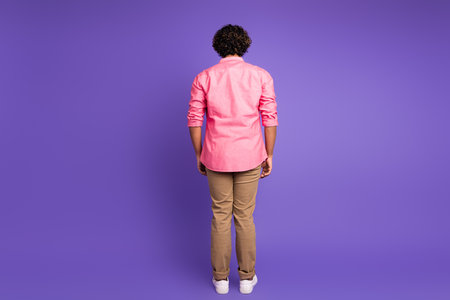 Full size rear photo of nice young man wear shirt isolated on violet color backgroundの写真素材