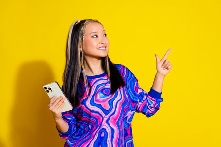 Photo of cute girl with dyed hair dressed shirt hold smartphone look directing at logo empty space...