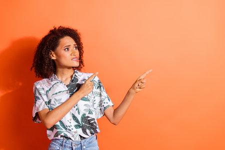 Photo of uncertain girl look point finger empty space isolated bright color backgroundの写真素材