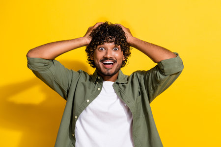 Portrait photo of young latin guy in khaki shirt surprised black friday sale low prices isolated on yellow color backgroundの写真素材