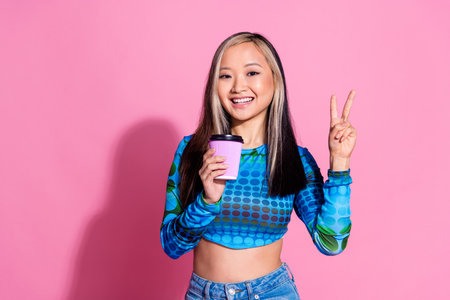 Photo of shiny attractive lady dressed print shirt enjoy beverage showing v-sign empty space...