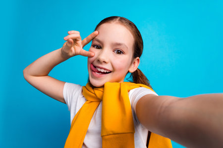 Photo of charming positive girl wear white t-shirt stick out recording video showing v-sign empty...