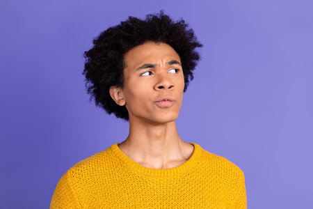 Photo of minded funny man wear trendy yellow clothes look empty space isolated on purple color...