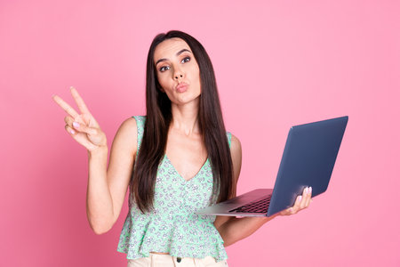 Photo of glamour lovely cute woman wear trendy clothes hold gadget netbook v-sign isolated on pink color backgroundの写真素材