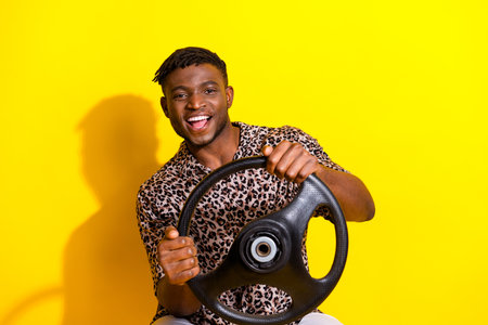 Photo of cool cheerful man wear summer trendy clothes drive fast new car isolated on bright yellow color backgroundの写真素材