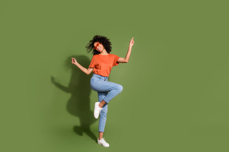 Full body photo of attractive young sunglass dancing dressed stylish orange clothes isolated on khaki color backgroundの写真素材