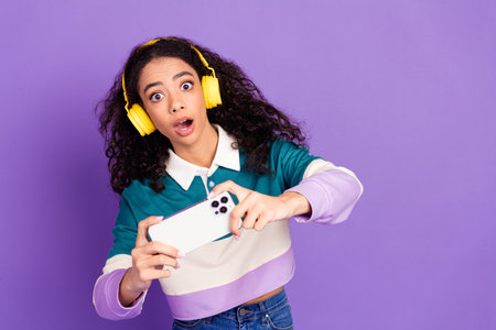 Portrait of lovely young girl play games wear shirt isolated on purple color backgroundの写真素材