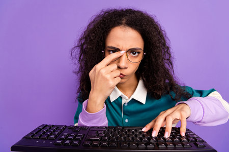 Portrait of lovely young girl typing keyboard wear shirt isolated on purple color backgroundの写真素材