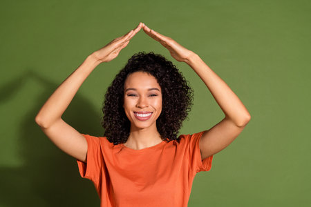 Photo portrait of lovely young lady hands roof gesture dressed stylish orange garment isolated on khaki color backgroundの写真素材