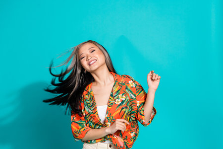 Photo of cheerful carefree lady dressed orange shirt smiling dancing empty space isolated blue color...