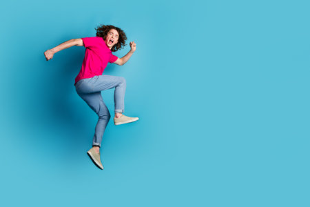 Full size photo of nice young man jump run empty space wear t-shirt isolated on blue color...