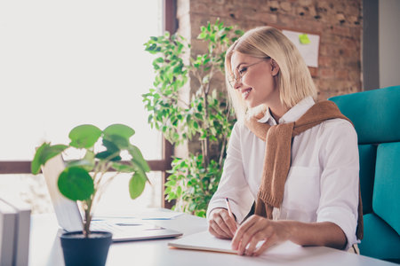 Photo of attractive young woman make notes notebook dressed trendy clothes executive business leader comfort beautiful office interiorの写真素材