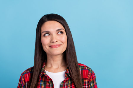 Photo portrait of attractive mature woman happy wear plaid red shirt looking minded plan empty space isolated on blue color backgroundの写真素材