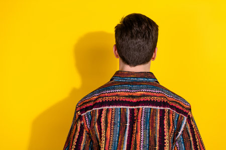 Rear photo of nice young man empty space wear shirt isolated on yellow color background