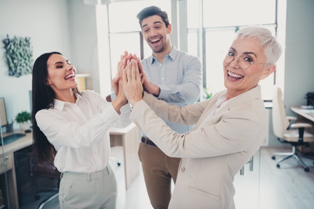 Photo of business people man women doing high five teambuilding concept in workplace workstation