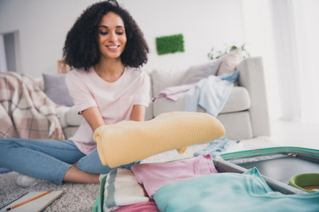Photo of lovely charming cute girl sitting floor preparing clothes valise weekend trip resortの写真素材