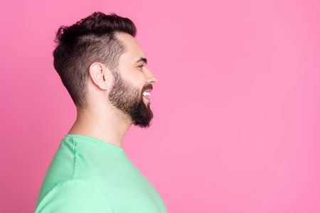 Side profile photo of nice guy with stylish beard dressed green t-shirt look at barbershop empty...