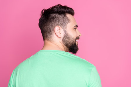 Side profile rear view photo of cheerful guy with beard dressed green t-shirt look at sale empty space isolated on pink color backgroundの写真素材