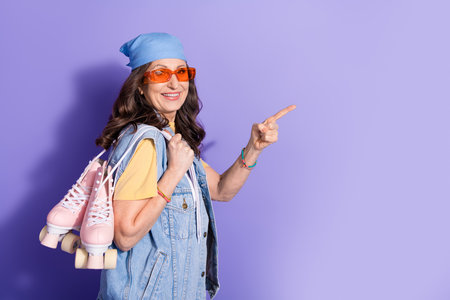 Photo of lovely pensioner lady roller skater point empty space dressed stylish denim hipster garment...