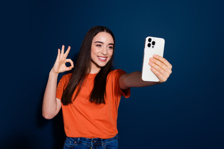 Photo of lovely adorable nice woman wear orange trendy clothes okey sign isolated on dark blue color backgroundの写真素材