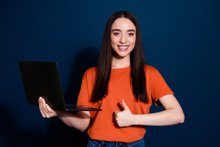 Photo of adorable pretty nice cute woman wear orange trendy clothes thumb up isolated on dark blue color backgroundの写真素材