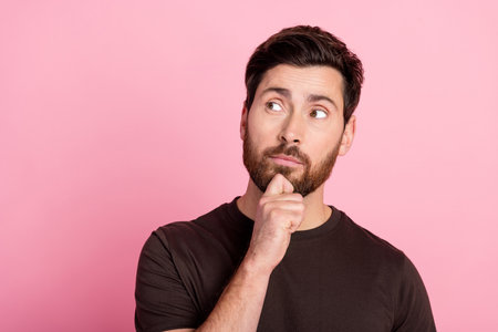 Portrait of minded man with bristle stylish hairdo wear brown shirt look at proposition empty space isolated on pink color backgroundの写真素材