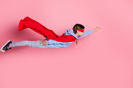 Full body portrait of cute little schoolkid superhero costume fly empty space isolated on pink color backgroundの写真素材