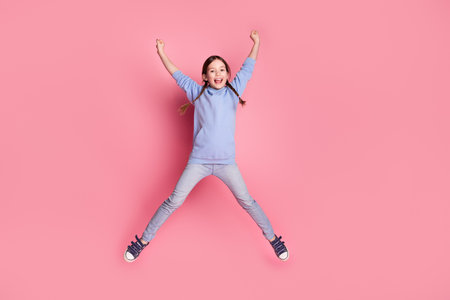 Full body portrait of cute little schoolkid jump raise fists wear hoodie isolated on pink color...