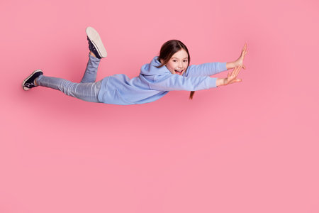 Full body portrait of cute little schoolkid fall fly wear hoodie isolated on pink color backgroundの写真素材