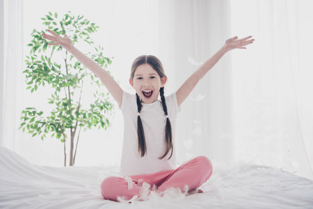 Full size photo of cute little girl throw feathers wear pajama comfy bed bedroom flat indoorsの写真素材
