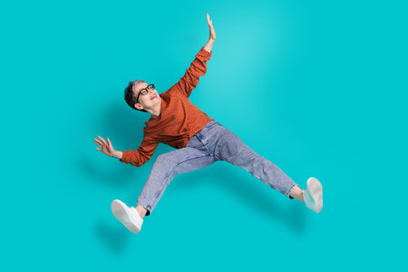 Full length photo of lovely pensioner lady excited funny levitate dressed stylish brown garment isolated on cyan color backgroundの写真素材
