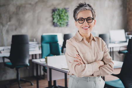Photo of attractive good mood age lady recruiter dressed formal shirt arms folded indoors workplace workstation loftの写真素材