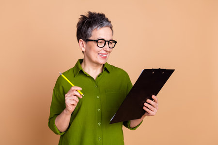 Photo portrait of lovely pensioner lady sign documents dressed stylish green garment isolated on...