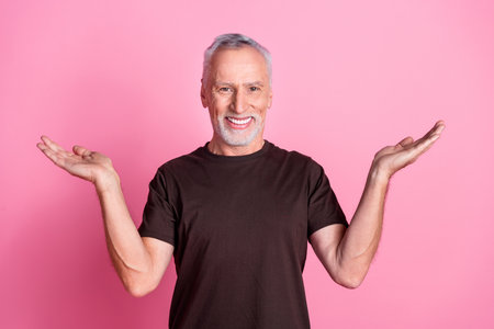 Portrait of nice man with white gray beard dressed brown t-shirt palms presenting products empty...