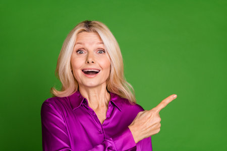Photo of attractive retired woman point amazed empty space dressed stylish violet satin clothes...