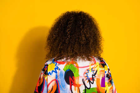 Photo portrait of attractive young woman back view show hair dressed stylish colorful print clothes isolated on yellow color backgroundの写真素材