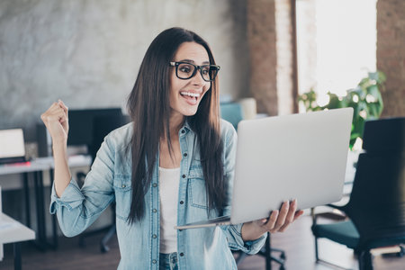 Photo of lucky good mood lady agent dressed jeans shirt winning game modern gadget indoors workplace...