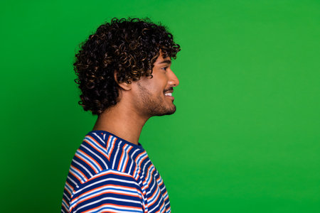 Profile side photo of positive funny man wear trendy striped clothes look empty space isolated on green color backgroundの写真素材