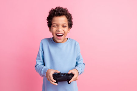 Photo of attractive funny grandson wear blue pullover enjoying console game empty space isolated pink color backgroundの写真素材