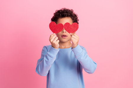 Photo of attractive funny grandson wear blue pullover rising two red hearts emtpy space isolated pink color backgroundの写真素材