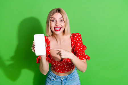 Photo of gorgeous lovely nice girl wear red stylish clothes hold device empty space isolated on green color backgroundの写真素材