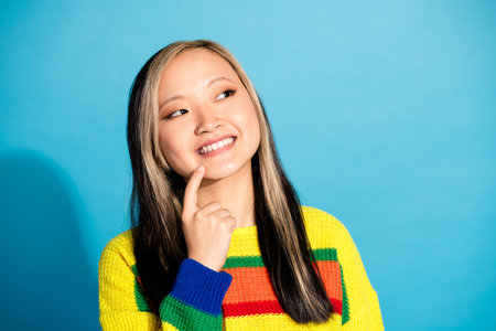 Photo portrait of lovely young lady look interested empty space dressed stylish striped garment isolated on blue color backgroundの写真素材