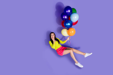 Photo of excited impressed lovely girl wear trendy clothes hold helium balloon empty space isolated on purple color backgroundの写真素材