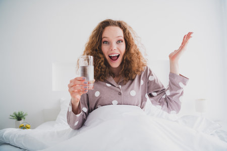 Portrait of nice young girl hold fresh water wear pajama bright interior bedroom flat indoorsの写真素材