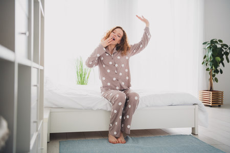 Full size photo of pretty young girl stretch yawn wear pajama bright interior bedroom apartment indoorsの写真素材